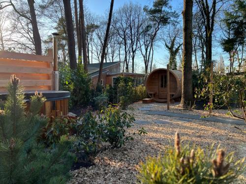a garden with a wooden house in the woods at Forest Bungalow 1 - Hottub - Nature - Relax in Rheezerveen