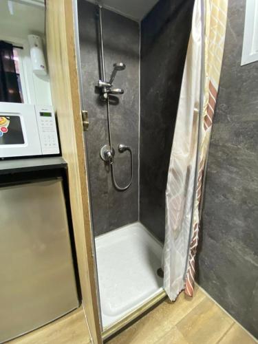 a shower stall in a kitchen next to a microwave at קראוון רעננה in Ra‘ananna