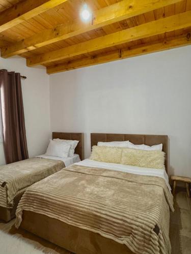two beds in a room with wooden ceilings at Bujtina Miqesia in Theth
