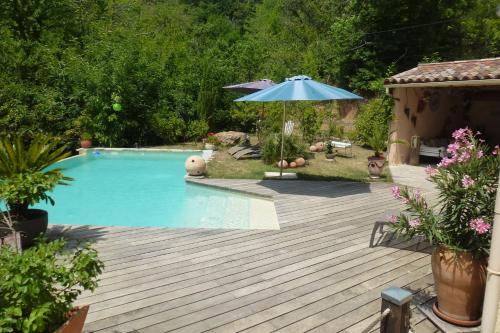 - une piscine avec un parasol et une terrasse en bois dans l'établissement Chambres d'hôtes de Charme Le Temps de Vivre, à Molières-Cavaillac