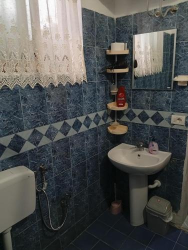 a blue tiled bathroom with a sink and a mirror at Arta room in Durrës