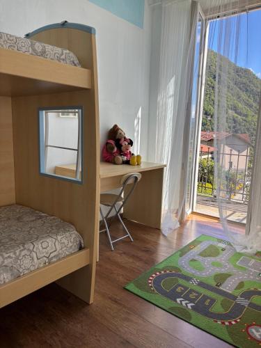 a bedroom with a bunk bed with a desk and a window at Charming & bright apartment Como lakefront in Argegno