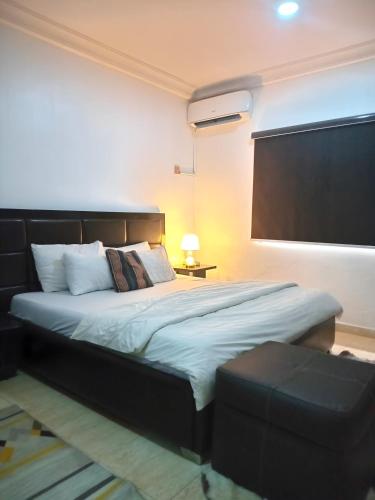 a bedroom with a large bed with a black headboard at The Bougainville Apartments in Asaba