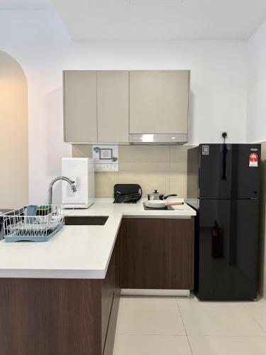 a kitchen with a black refrigerator and brown cabinets at Suria Garden by Iconique in Puchong