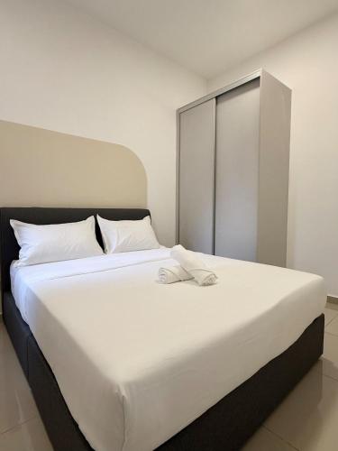 a large white bed with white sheets and pillows at Suria Garden by Iconique in Puchong