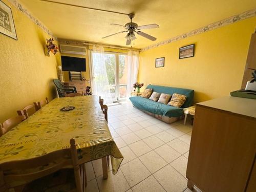 un salon avec une table et un canapé bleu dans l'établissement Appartement T3 Provençal avec Parking et Animaux admis, à 700m de la Plage - FR-1-799-54, au Barcarès