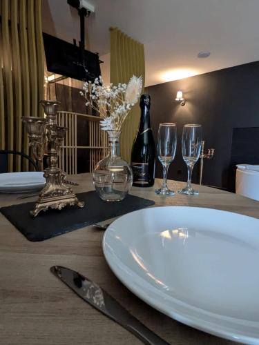 - une table avec une assiette blanche et deux verres à vin dans l'établissement jacuzzi, massage table, relaxation, wedding, loveroom, à Wizernes