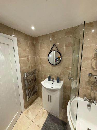 a bathroom with a sink and a shower and a mirror at Cosy 2 Bed Cardiff Bay Retreat! in Cardiff