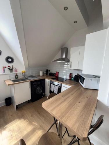 カーディフにあるCosy 2 Bed Cardiff Bay Retreat!のキッチン(木製テーブル、白いキャビネット付)