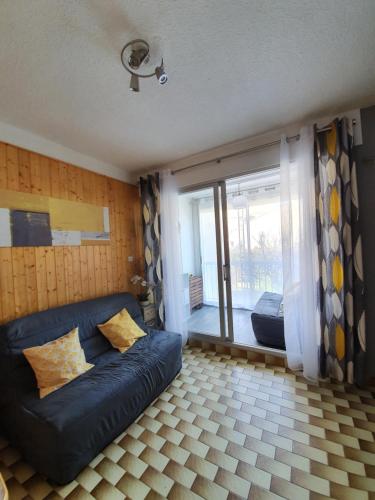 un salon avec un canapé bleu et une fenêtre dans l'établissement Valras-plage studio cabine 100m de la plage, à Valras-Plage