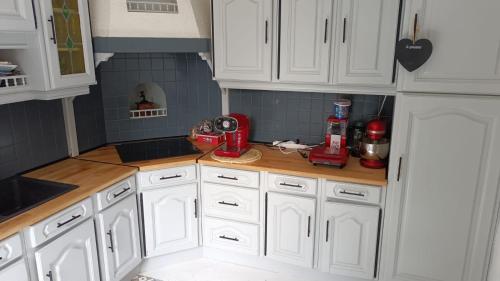 une cuisine avec des armoires blanches et un appareil rouge sur un comptoir dans l'établissement Belle maison proche du futuroscope, à Thuré