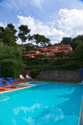 a swimming pool with blue chairs and a building at Residence Vistamare La Fonte in Nisporto