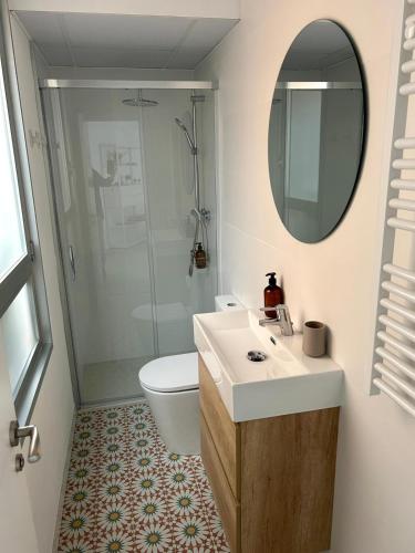 ein Badezimmer mit Toilette, Waschbecken und Spiegel in der Unterkunft BERENGUER HUESCA con parking in Huesca