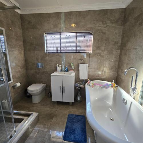 a bathroom with a tub and a toilet and a sink at Cosy Villa in Stegi