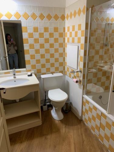 une femme prenant une photo d'une salle de bains avec toilettes et lavabo dans l'établissement Charmant appartement dans résidence avec piscine vue mer, à Cannes