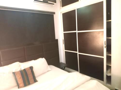 a bed with a black headboard and white pillows at The Bougainville Apartments in Asaba