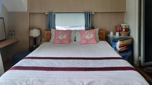 a bedroom with a bed with pink pillows at NEST House in Ấp Kim Thạch