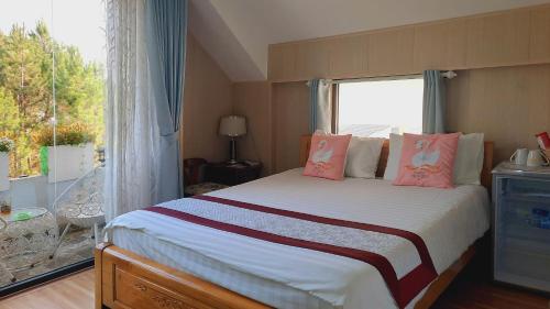 a bedroom with a bed with pink pillows and a window at NEST House in Ấp Kim Thạch