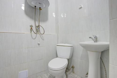 a white bathroom with a toilet and a sink at Частный сектор in Bosteri