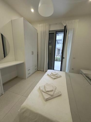 a white bedroom with two white towels on a bed at Oristay Aprtement in Polisi i Vogël