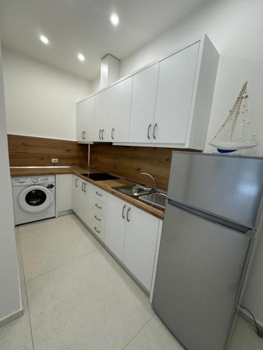 a white kitchen with a refrigerator and a sink at Oristay Aprtement in Polisi i Vogël