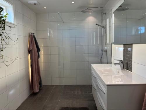 a white bathroom with a sink and a mirror at Villa Borgholm - Öland in Borgholm