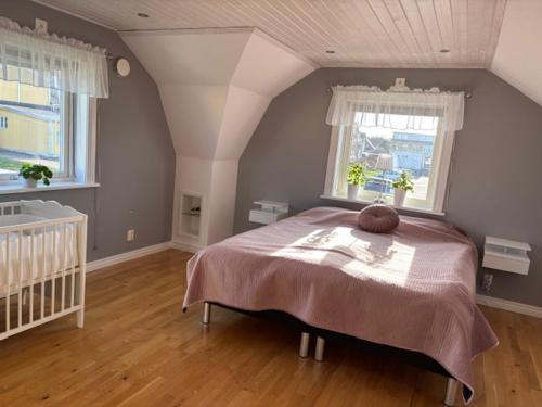 a bedroom with a large bed and two windows at Villa Borgholm - Öland in Borgholm