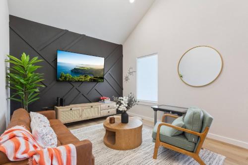 a living room with a couch and a tv on a wall at Stay in Luxury near Baylor University & Downtown in Waco