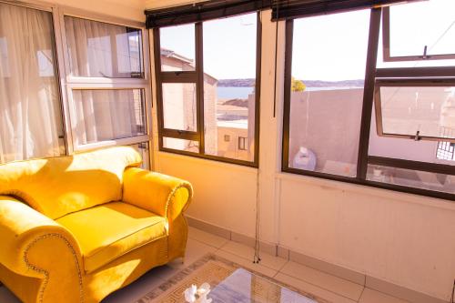 a yellow chair in a room with windows at The View Apartment 5 in Lüderitz
