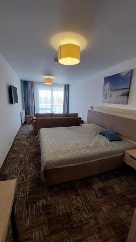 a bedroom with a large bed and a couch at Apartament Sand Welle in Grzybowo