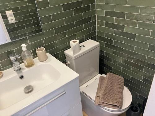 La salle de bains est pourvue d'un lavabo, de toilettes et de carrelage vert. dans l'établissement Appartement Boutonnet Montpellier, à Montpellier