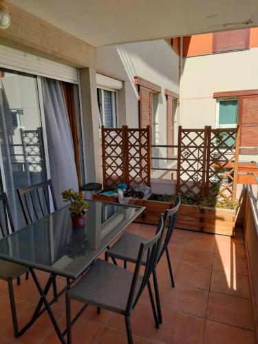d'une terrasse avec une table en verre et des chaises sur un balcon. dans l'établissement Appartement T3 équipé idéal curiste avec parking, au Boulou