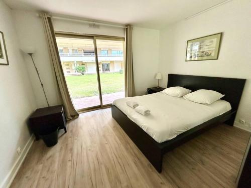 une chambre avec un grand lit et une grande fenêtre dans l'établissement The golden triangle Apartment, à Deauville