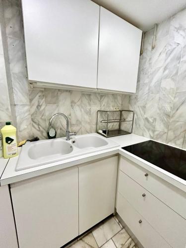 une cuisine avec des armoires blanches et un évier dans l'établissement The golden triangle Apartment, à Deauville