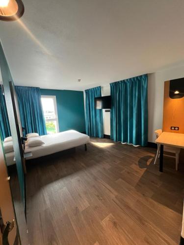 a room with a bed and blue curtains at B&B HOTEL Paris Romainville Noisy-le-Sec in Romainville