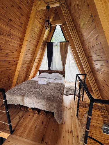 ein Schlafzimmer in einem Blockhaus mit einem großen Fenster in der Unterkunft Sunny Side - მზიანი მხარე in K'eda