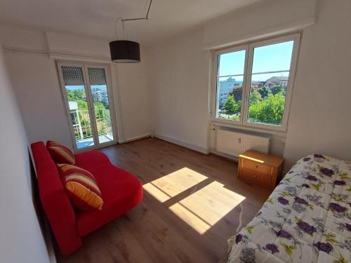 a bedroom with a red chair and two windows at Odeon A near Basel in Huningue