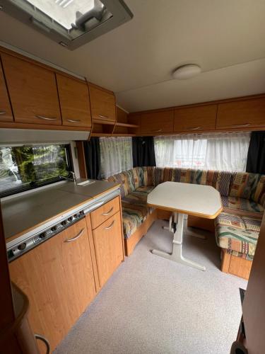 an rv kitchen with a couch and a table at Vintage przyczepa JustarniaCamp in Jastarnia