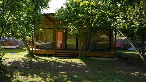 a small cabin in a garden with a swing at Dumbo Eco Camp in Ozurgetʼi