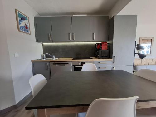 a kitchen with a black table and white chairs at Studio au coeur d'Avoriaz - 4 pers - vue splendide in Avoriaz