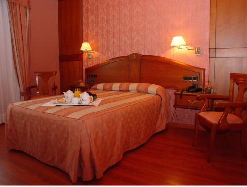 Una habitación de hotel con una cama con una bandeja de comida. en Hotel Torres I, en Villanueva del Arzobispo