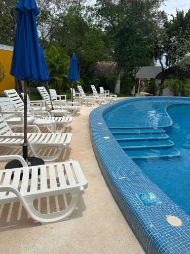 a pool with chairs and umbrellas next to a swimming pool at Club Cenotes Tulum in Balcheil