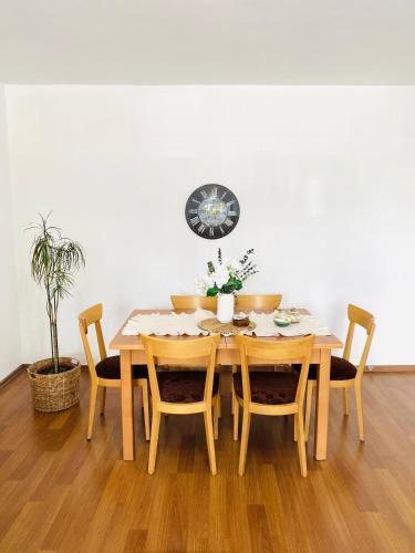 a dining room table with chairs and a clock on the wall at Aydınoğlu Suites in Denizli