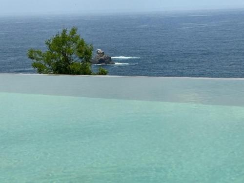 a large body of water with a rock in the ocean at La Alberca Hotel Boutique in Mazunte