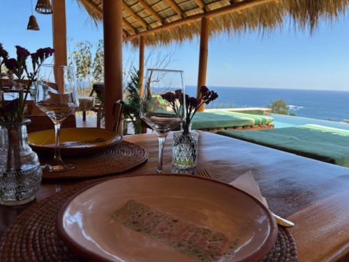 a table with a plate of food and wine glasses on it at La Alberca Hotel Boutique in Mazunte