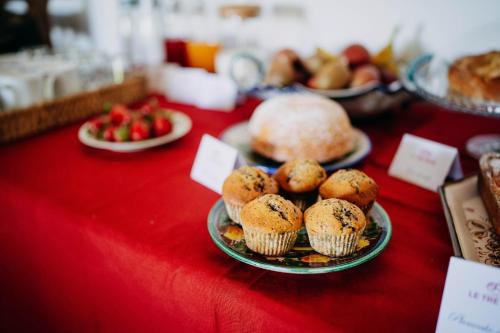 a red table topped with plates of muffins and fruit at Tenuta Le Tre Rose in Vibonati