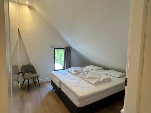 a bedroom with a white bed and a chair at Modern Polderhuis Zeeland Philippine in Philippine