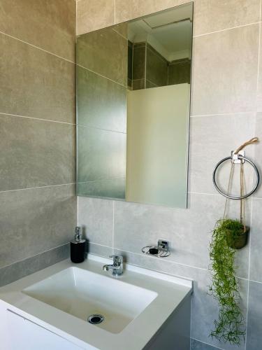 ein Badezimmer mit einem weißen Waschbecken und einem Spiegel in der Unterkunft White Oasis in Gaborone