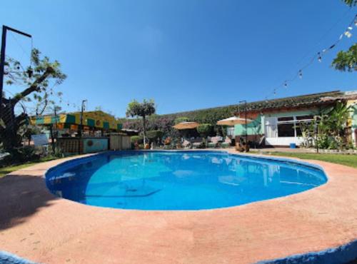 une grande piscine bleue dans une cour dans l'établissement Hotel posada el paraíso, à Tepoztlán