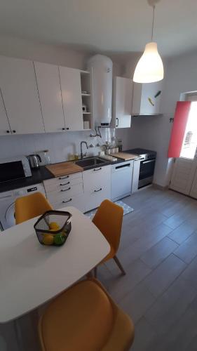 a kitchen with white cabinets and a table and chairs at Não te vou esquecer Aldeia da Luz! in Luz